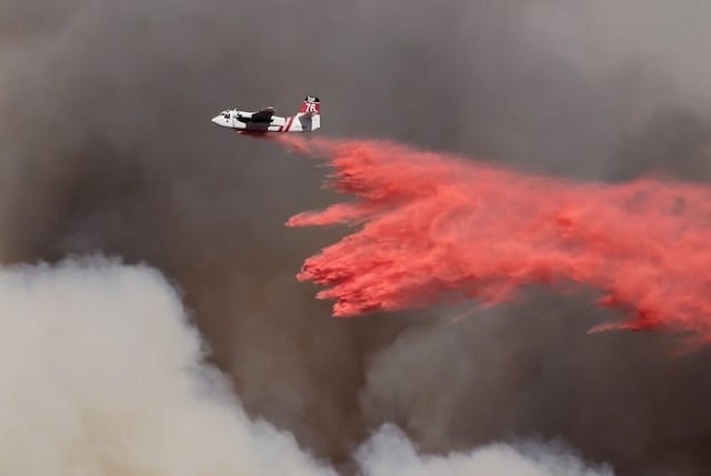 An airplane releases fire retardant over a wildfire
